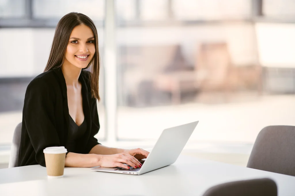 Una mujer trabaja desde su laptop en un ambiente luminoso, representando qué es un software contable al facilitar la organización de registros y reportes financieros.