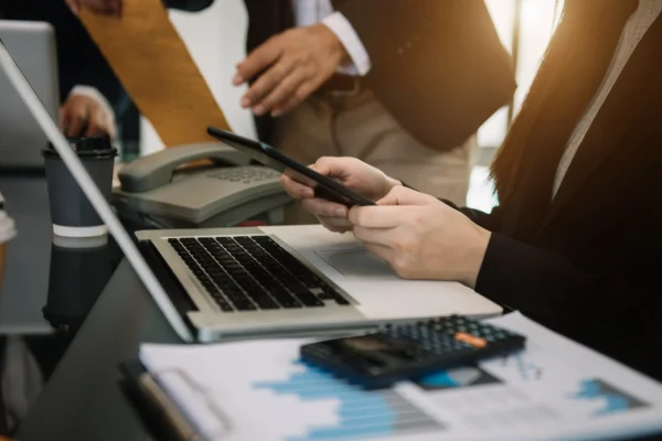 Colaboradores trabajando en un sistema de cobranza, usando una computadora y revisando documentos financieros.