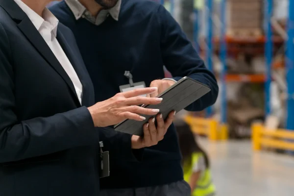Colaboradores en un almacén revisando inventarios en tiempo real mediante un tablet, implementando un sistema de control de inventarios eficiente.