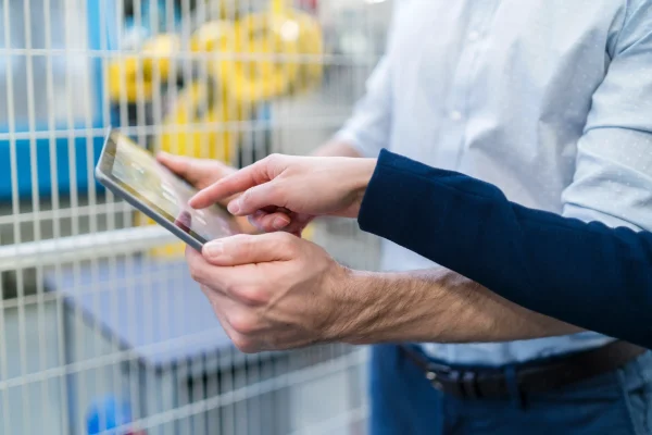 Colaboradores en almacén utilizando un tablet para registrar productos y gestionar inventarios mediante un sistema de control de inventarios.