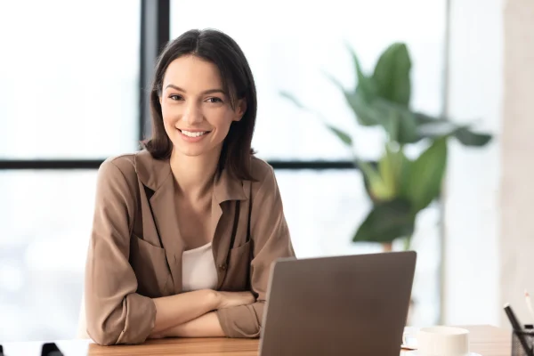 Una mujer sonríe frente a su computadora tras gestionar aspectos que muestra lo que hace un software de nómina.
