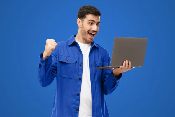 Un hombre celebra frente a su laptop, tras confirmar cómo saber si tengo saldo a favor en el SAT.