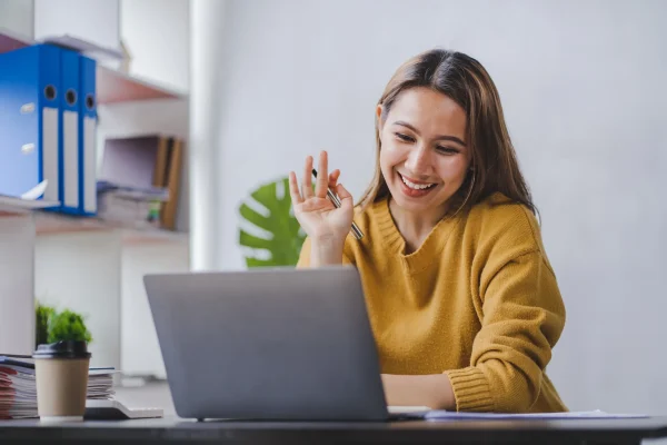 Videollamada en la que una mujer está resolviendo dudas relacionadas con cómo sé si tengo saldo a favor en el SAT. Una mujer sonriente interactúa frente a su laptop, quizás recibiendo asesoría virtual sobre cómo sé si tengo saldo a favor en el SAT.