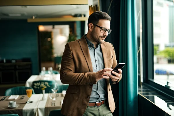 Este momento de pausa en el trabajo refleja la importancia de los descansos como medida preventiva dentro de la aplicación de la NOM 035. Un trabajador revisa información desde su celular en un entorno relajado, lo que podría formar parte de una estrategia empresarial enfocada en la NOM 035.