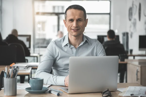 Un usuario se encuentra concentrado en su laptop dentro de un ambiente de trabajo, realizando actividades que podrían relacionarse con el seguimiento de formación a través de CONTPAQi® Kursa. En una oficina moderna, un hombre frente a su computadora tomando capacitaciones en línea con herramientas como CONTPAQi® Kursa.