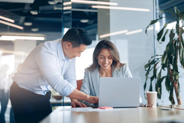 Reunión de trabajo frente a una computadora portátil para procesos de revisión de XMLs con plataformas como CONTPAQi® XML en línea +. Un hombre y una mujer revisan información en una laptop en un espacio de oficina, mientras usan herramientas como CONTPAQi® XML en línea +.