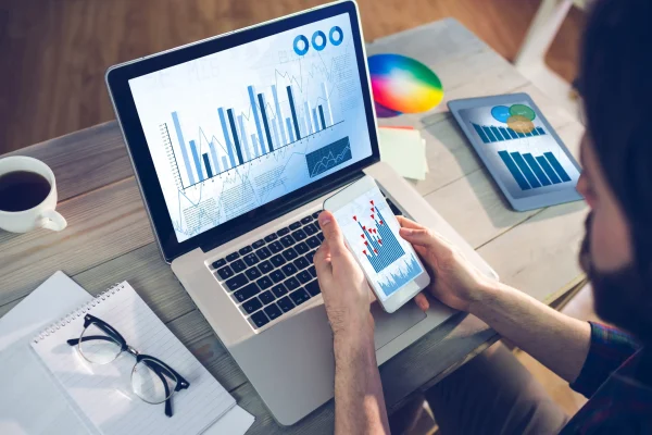Vista de una laptop y un celular con gráficas de desempeño generadas mediante el software CONTPAQi Contabiliza®. Dispositivos mostrando reportes gráficos y estadísticas, como parte del análisis de datos con CONTPAQi Contabiliza®.
