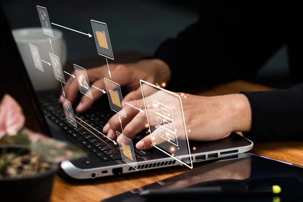 Interacción directa con una laptop y elementos visuales que representan estructuras digitales, simulando acciones como las realizadas con CONTPAQi® Timbra al timbrar documentos fiscales. Las manos de una persona escriben en una laptop mientras gráficos digitales de archivos flotan sobre la imagen, representando procesos asociados al uso de plataformas como CONTPAQi® Timbra.