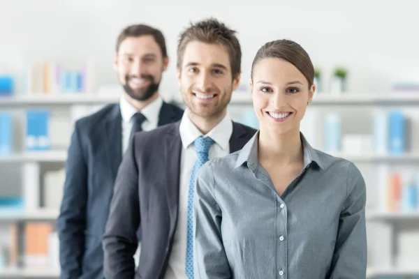 Dos hombres y una mujer en ropa formal posan juntos, simbolizando el respaldo de un distribuidor CONTPAQi capacitado. Grupo de profesionales sonrientes representa al equipo humano que colabora en soluciones de un distribuidor CONTPAQi.