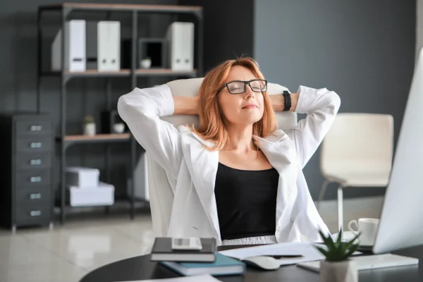 En una oficina, una mujer se recuesta satisfecha, disfrutando de un momento de descanso, tal vez tras recibir su prima vacacional en México. Una mujer luce relajada en su espacio de trabajo, reflejando la tranquilidad que puede brindar recibir la prima vacacional en México.