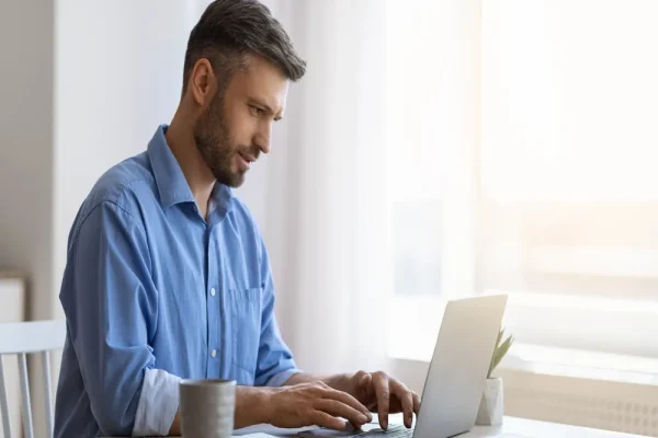 Hombre de camisa azul revisa en su computadora los datos necesarios para elaborar una carta porte antes de un envío.
