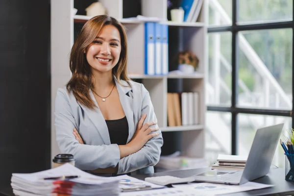 Una mujer de negocios sonríe con confianza en un entorno laboral, proyectando liderazgo en el uso de Contpaqi Nóminas.