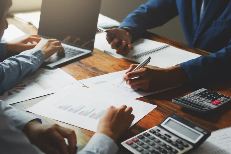 Un grupo de personas analiza reportes financieros y planillas mientras revisan cómo automatizar el cálculo de impuestos y deducciones en la nómina.