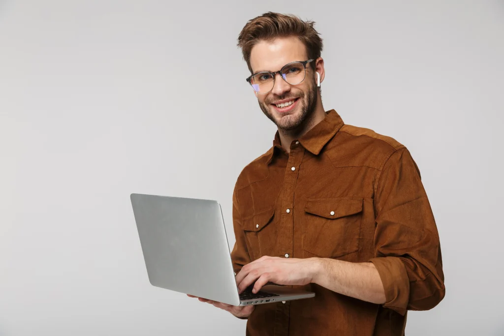 Hombre sonriente sostiene una laptop mientras gestiona su negocio a través de un sistema de facturación moderno y fácil de usar.
