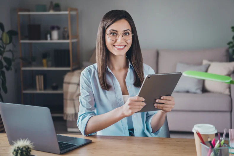 Una mujer trabajando con una tablet en un espacio moderno, mostrando cómo las soluciones tecnológicas para empresas facilitan la gestión de tareas y comunicación diaria.