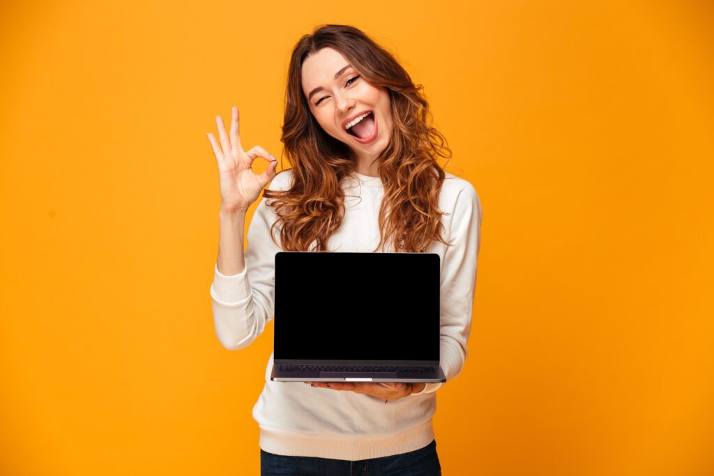 Una mujer sostiene su laptop con una expresión alegre tras comprender mejor como calcular aguinaldo.