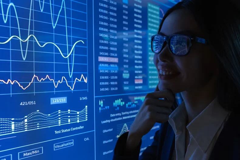 Vista enfocada de una mujer en donde se le pueden reflejar los gráficos financieros digitales.