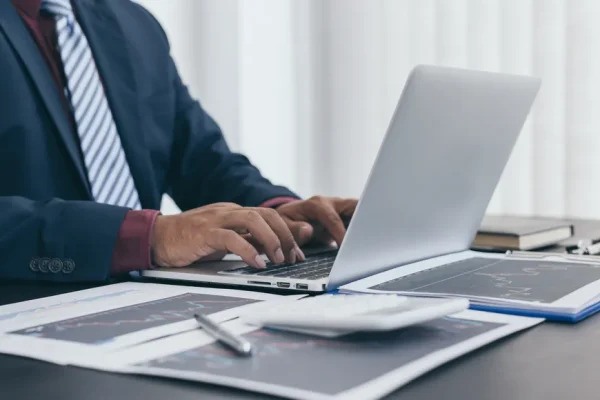 Un contador trabajando en una laptop con un sistema contable especializado, en un entorno corporativo.